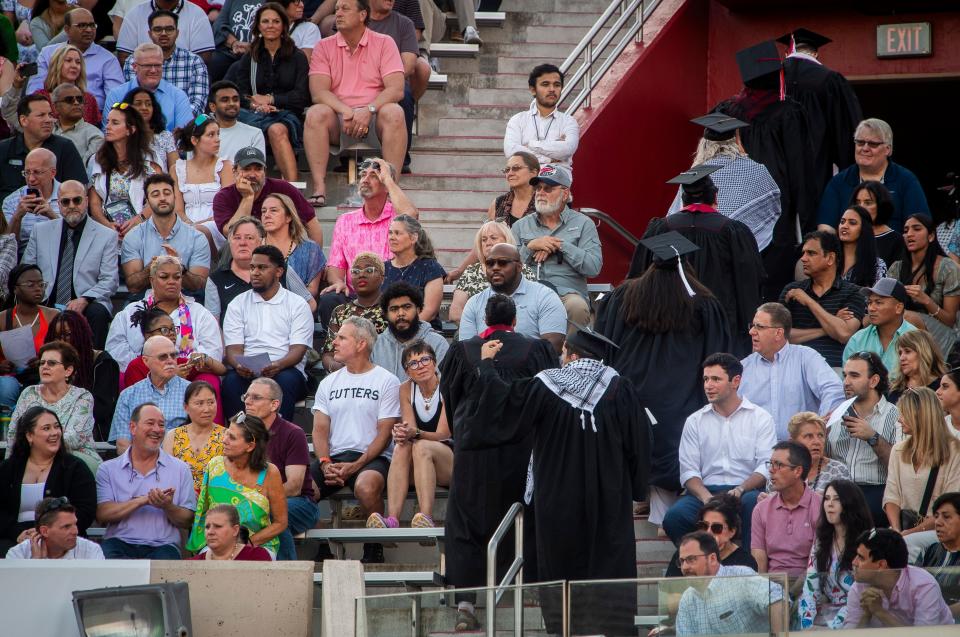 A group of students walks out as Indiana University President Pamela Whitten delivers remarks during undergraduate commencement proceedings at Memorial Stadium on Saturday.