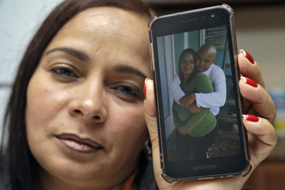 In this Wednesday, Feb. 26, 2020 photo, Yarelis Gutierrez Barrios holds up a cell phone photo at her home in Tampa, Fla., of herself with her partner Roylan Hernandez Diaz, a Cuban asylum seeker who hanged himself in a Louisiana prison. An Associated Press investigation into Hernandez’s death last October found neglect and apparent violations of government policies by jailers under U.S. Immigration and Customs Enforcement. (AP Photo/Chris O'Meara)
