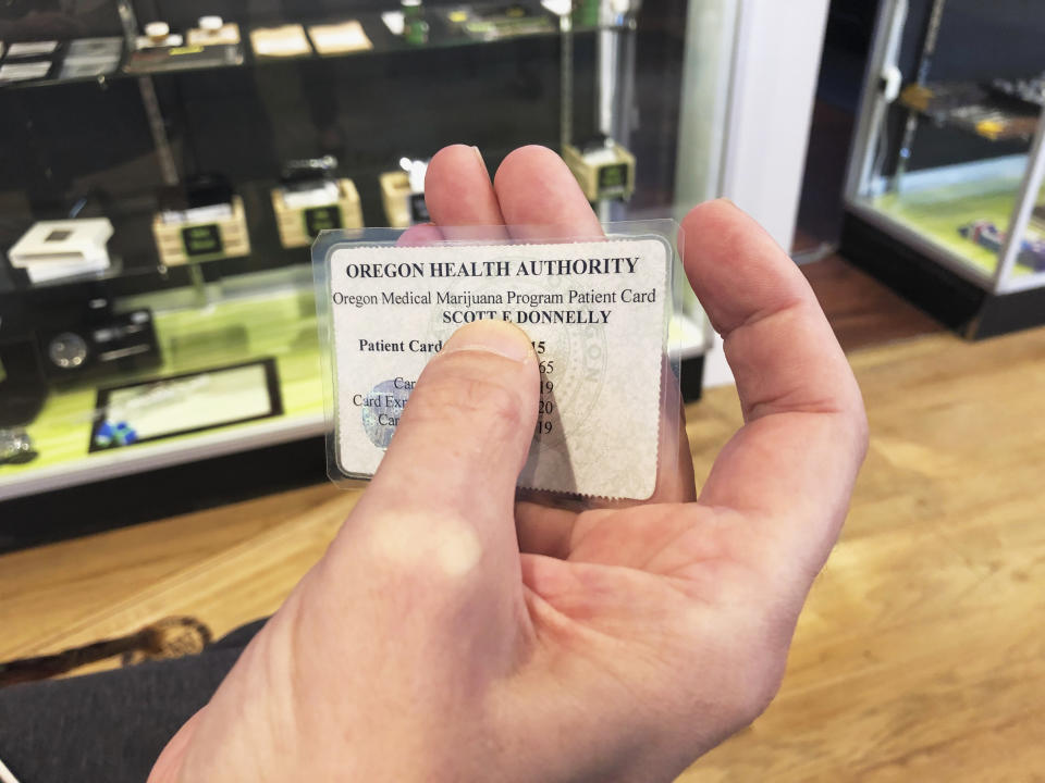 ADVANCE FOR PUBLICATION ON TUESDAY, JUNE 11, AND THEREAFTER - In this April 26, 2019, photo, medical marijuana cardholder Scott Donnelly shows his card issued by the state of Oregon in Sherwood, Ore. Donnelly visits a medical-only dispensary once a week to buy cannabis to help with muscle spasms caused by his multiple sclerosis. The dispensary is one of two medical-only shops left in Oregon. (AP Photo/Gillian Flaccus)