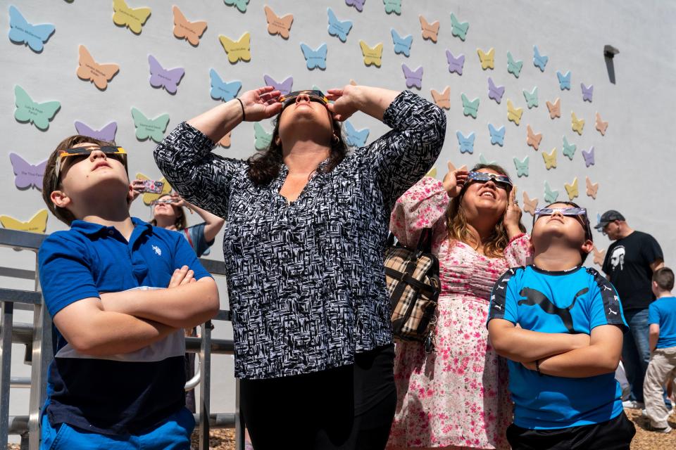 Collin and Colleen Barbee, left, and Jessica and M.J. Abalos, watch the partial solar eclipse at the Cox Science Center on April 8, 2024 in West Palm Beach, Florida.