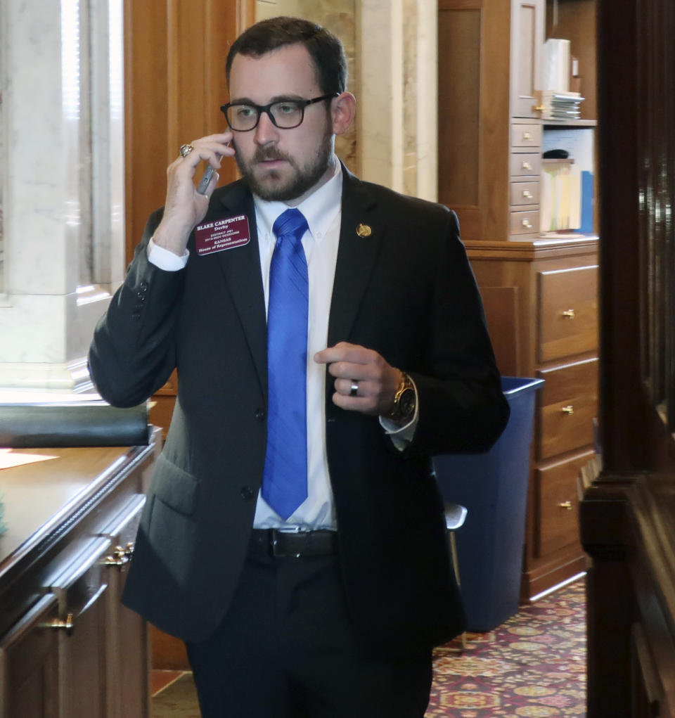 Kansas state Rep. Blake Carpenter, R-Derby, talks on his cell phone behind the House speaker's dais during a break in the House's session, Saturday, May 4, 2019, at the Statehouse in Topeka, Kan. Medicaid expansion supporters were holding up a proposed state budget in the House in hopes of forcing a debate on expansion in the Senate, and Carpenter opposes the expansion plan. (AP Photo/John Hanna)