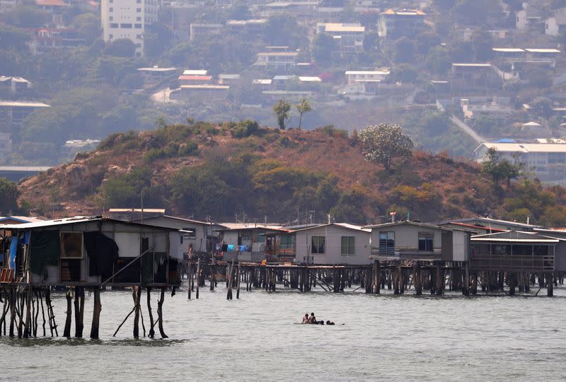 FILE PHOTO: Newly constructed apartment blocks are seen behind the stilt house village called Hanuabada, located in Port Moresby Harbour in Papua New Guinea