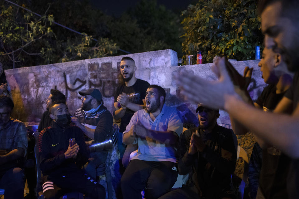 Palestinians sing during an ongoing protest against the forcible eviction of Palestinians from their homes in the Sheikh Jarrah neighborhood of east Jerusalem, Friday, May 7, 2021. Dozens of Palestinian families in east Jerusalem are at risk of losing their homes to Jewish settler groups following a decades-long legal battle. The threatened evictions have sparked weeks of protests and clashes in recent days, adding to the tensions in Jerusalem. (AP Photo/Maya Alleruzzo)