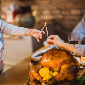 family around the thanksgiving table pulling on a wishbone