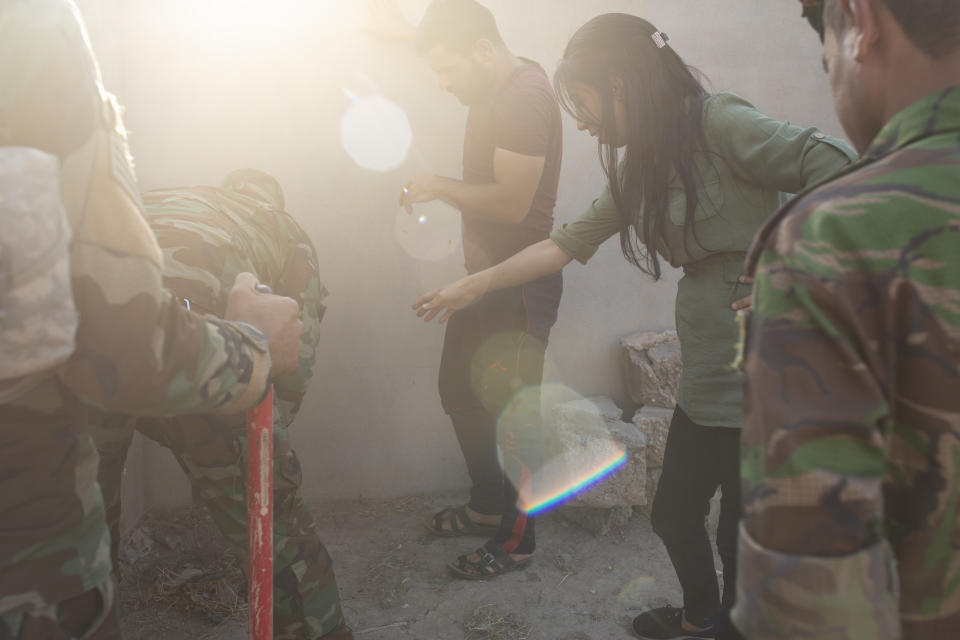 In this Aug. 31, 2019 photo, Layla Taloo directs security forces digging in the garden where she buried her mobile phone and cigarettes while being held by Islamic State militants in 2014, in Tal Afar, Iraq. She was abducted by the extremists along with her husband and children — but once her husband was taken away, Taloo was sold to an Iraqi doctor, who three days later gifted her to a friend. Despite the rules mandating sales through courts, she was thrown into a world of informal slave markets run out of homes. (AP Photo/Maya Alleruzzo)