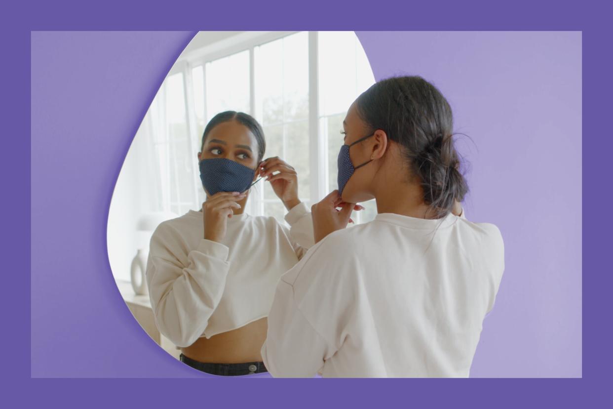 maskitis , What to Do If Your Face Mask Is Causing a Rash , Black African American female puts on a protective face mask before leaving her apartment. COVID-19 pandemic, preventive measures of coronavirus