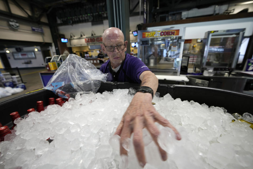 As temperatures soar into the triple digits for the third straight day, vendor James Oehlerking spreads ice over a tub of bottled beer to prepare the drinks for sale on the main concourse of Coors Field before the first inning of a baseball game Thursday, June 17, 2021, in Denver. (AP Photo/David Zalubowski)