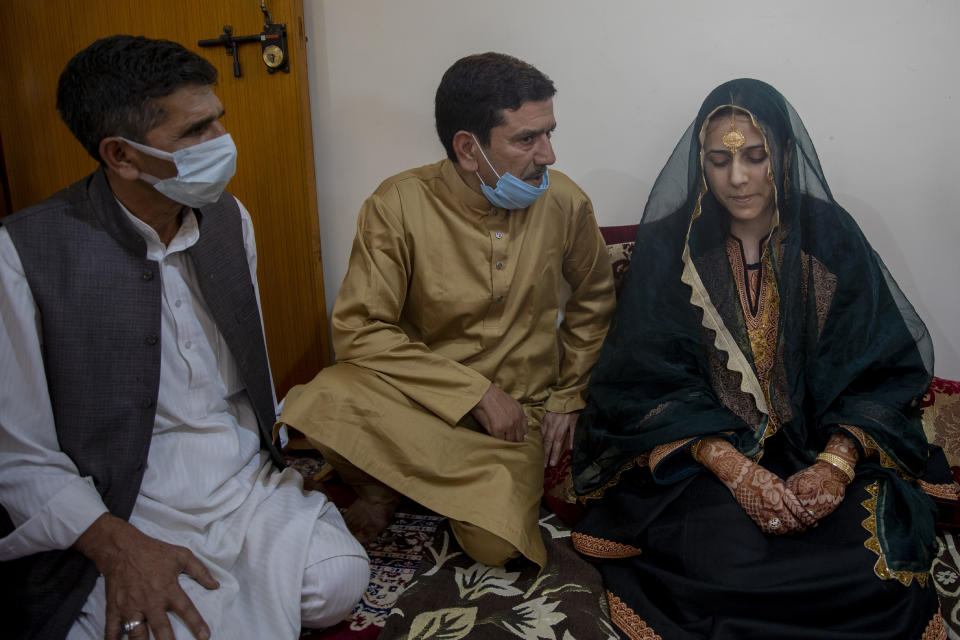 Fayaz Ahmed, center and Manor Ahmed, left, uncles of Kashmiri bride Saima Ashraf, ask her permission before Nikah ceremony during a wedding on the outskirts of Srinagar, Indian controlled Kashmir, Thursday, Sept. 17, 2020. The coronavirus pandemic has changed the way people celebrate weddings in Kashmir. The traditional week-long feasting , elaborate rituals and huge gatherings have given way to muted ceremonies with a limited number of close relatives attending. With restrictions in place and many weddings cancelled, the traditional wedding chefs have little or no work. The virus has drastically impacted the life and businesses in the region. (AP Photo/ Dar Yasin)