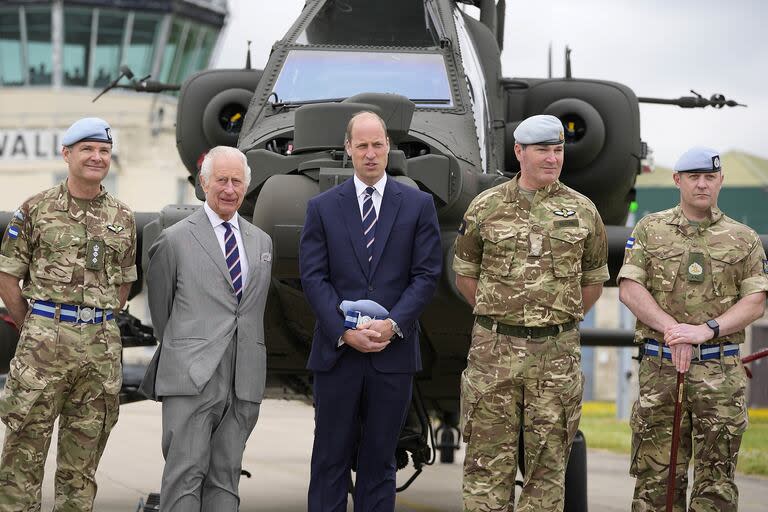 El Rey Carlos III de Gran Bretaña posa con personal de servicio después de entregar oficialmente el cargo de Coronel en Jefe del Cuerpo Aéreo del Ejército al Príncipe Guillermo, Príncipe de Gales, delante de un helicóptero Apache en el Centro de Aviación del Ejército en Middle Wallop, Inglaterra, el lunes 13 de mayo de 2024. (AP Photo/Kin Cheung, Pool)