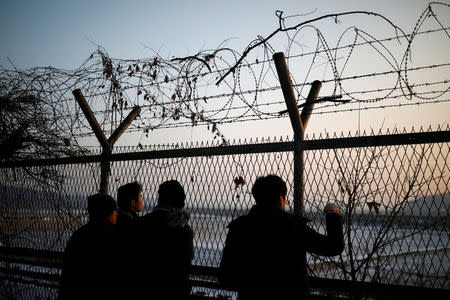 People look toward the north through a barbed-wire fence near the militarized zone separating the two Koreas, in Paju, South Korea, December 21, 2017. REUTERS/Kim Hong-Ji/Files
