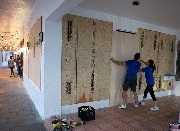 Luca Leguerchois (left) and Eglantine Leguerchois board up their Paradise Sweets store in preparation for Hurricane Ian on September 26, 2022, in St. Petersburg, Florida.