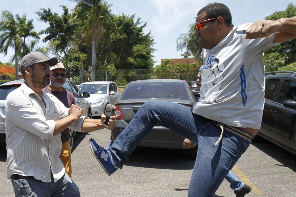 A supporter of Venezuelan President Nicolas Maduro kicks a supporter of Venezuelan opposition leader and self-proclaimed interim president Juan Guaido, outside the Venezuelan Embassy, in Brasilia, Brazil, Wednesday, Nov. 13, 2019. A group of people backing Guaido have occupied the nation's embassy in Brasilia. (AP Photo/Beto Barata)
