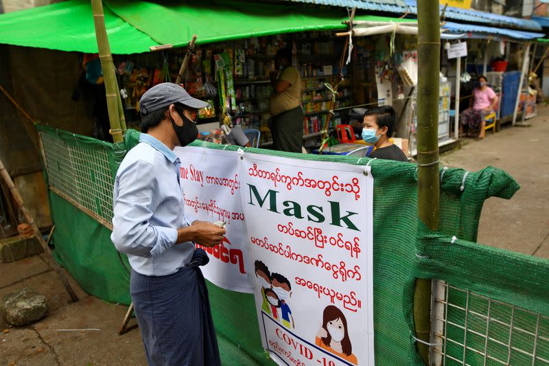 People chat with a barricade between them blocking off their street to prevent the spread of the coronavirus disease in Yangon