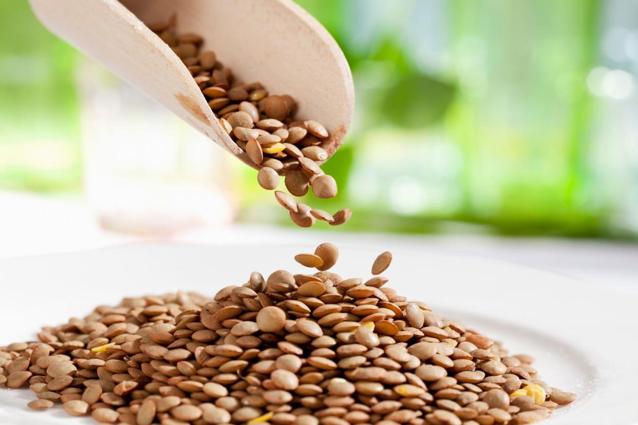 lentils pouring from wooden scoop, close up