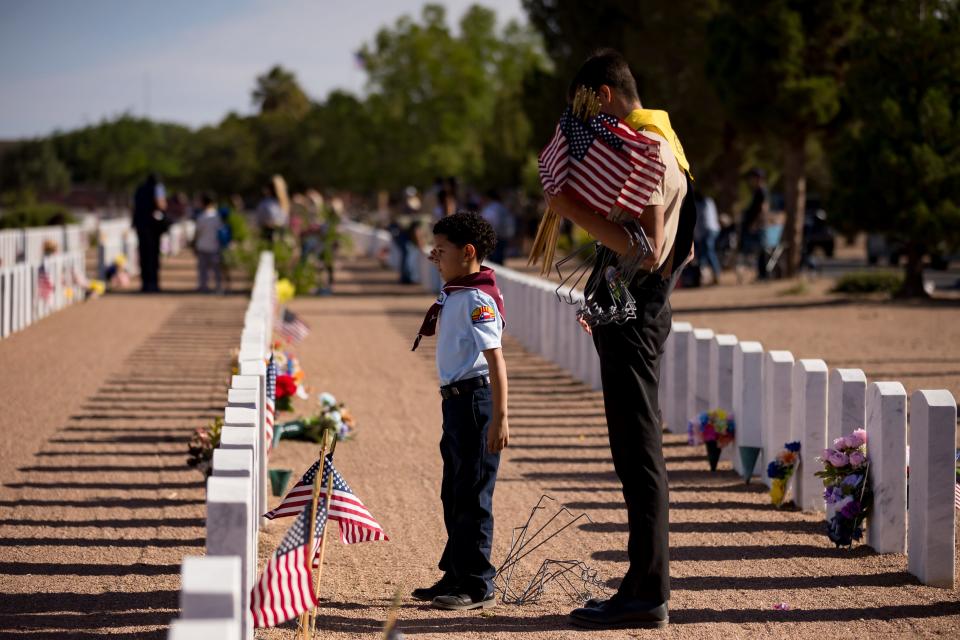 Scouting America troops, formerly Boy Scouts of America, salute after they place flags on the graves at Fort Bliss Cemetery before Memorial Day on Saturday, May 25, 2024.