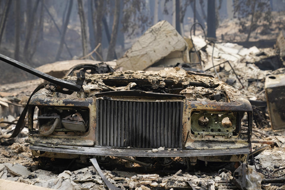A charred vehicle is parked in front of a home after the CZU Lightning Complex Fire went through Sunday, Aug. 23, 2020, in Boulder Creek, Calif. (AP Photo/Marcio Jose Sanchez)