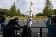 Former Olympian Aya Terakawa, center, participating as an Olympic torch relay runner, waves as she carries the torch during the first day of the Osaka round at a former Expo site in Suita, north of Osaka, western Japan, Tuesday, April 13, 2021. The Tokyo 2020 Olympic kick-off event which was rescheduled due to the coronavirus outbreak was yet rearranged to hold at the former Expo park, instead of public streets, to close off the audience from the even, following the mayor's decision as Osaka has had sharp increases in daily cases since early March. (AP Photo/Hiro Komae)