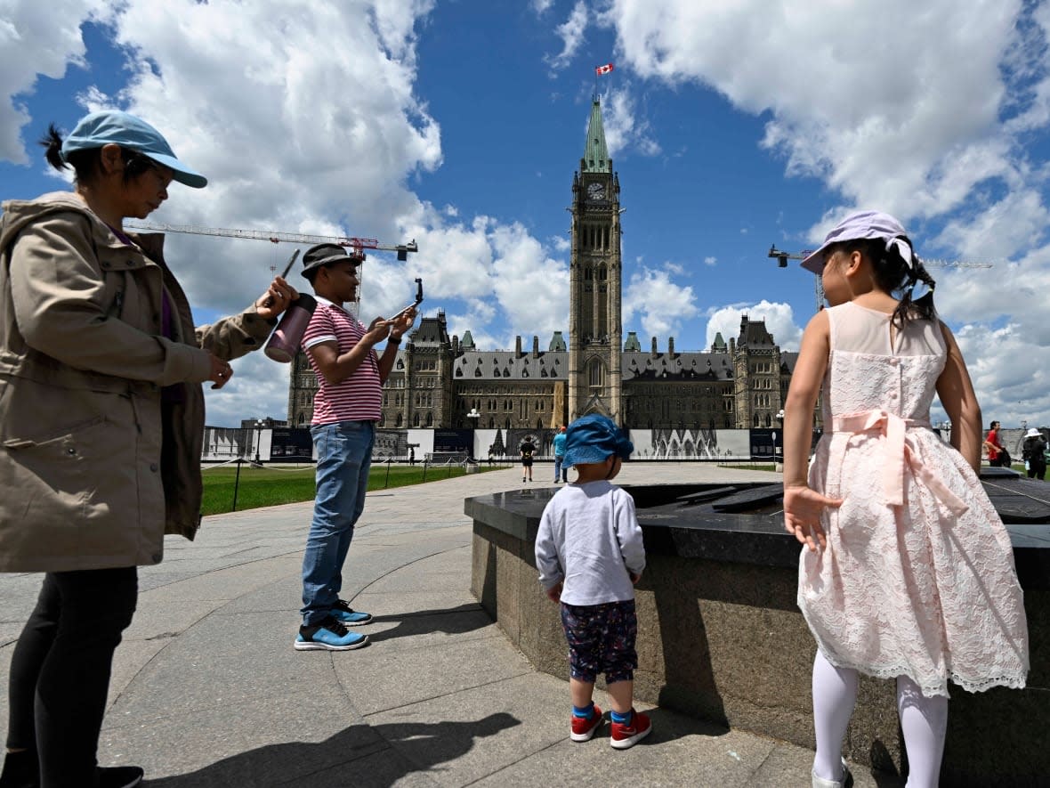 Visitors to Parliament Hill take in the Centennial Flame in front of the Peace Tower June 17, 2022. (Justin Tang/The Canadian Press - image credit)