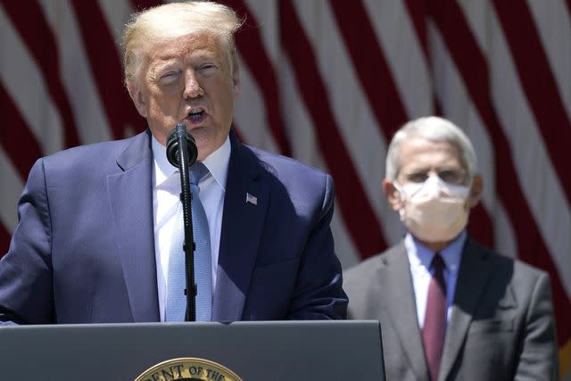 <p>Drew Angerer/Getty </p> President Donald Trump stands in front of Dr. Anthony Fauci while speaking about coronavirus vaccine development in the White House Rose Garden on May 15, 2020