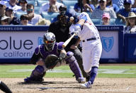 Los Angeles Dodgers' Chris Taylor, right, hits a three-run home run as Colorado Rockies catcher Tony Wolters, left, watches along with home plate umpire Paul Emmel, center, during the seventh inning of a baseball game Sunday, June 23, 2019, in Los Angeles. (AP Photo/Mark J. Terrill)