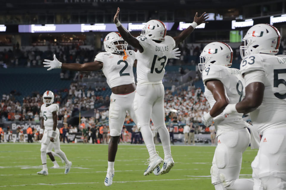 Miami running back DeeJay Dallas (13) celebrates with wide receiver K.J. Osborn (2) after scoring a touchdown during the first half of an NCAA college football game against Virginia, Friday, Oct. 11, 2019, in Miami Gardens, Fla. (AP Photo/Lynne Sladky)