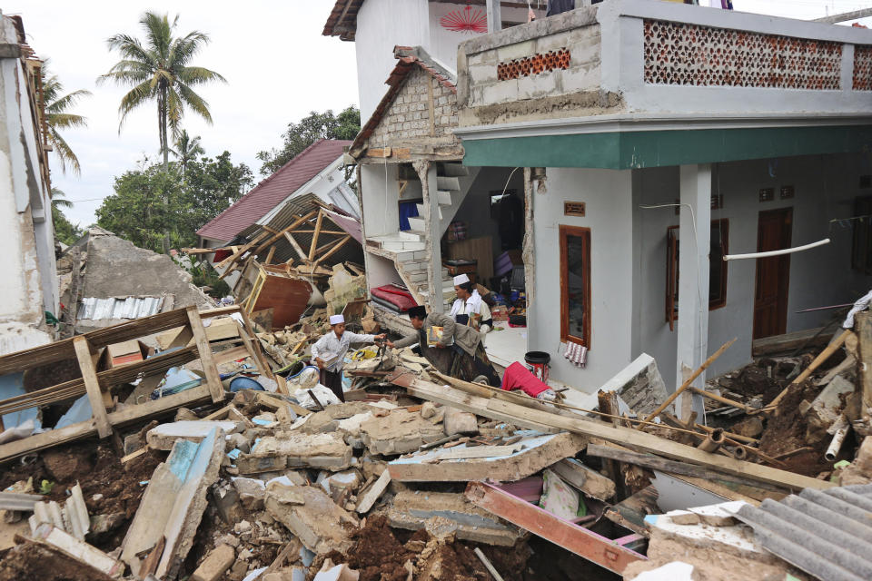 People salvage items from the rubble at the ruins of Al Buroq Islamic Boarding School which was badly damaged during Monday's earthquake, in Cianjur, West Java, Indonesia, Wednesday, Nov. 23, 2022. More rescuers and volunteers were deployed Wednesday in devastated areas on Indonesia's main island of Java to search for the dead and missing from an earthquake that killed hundreds of people. (AP Photo/Rangga Firmansyah)