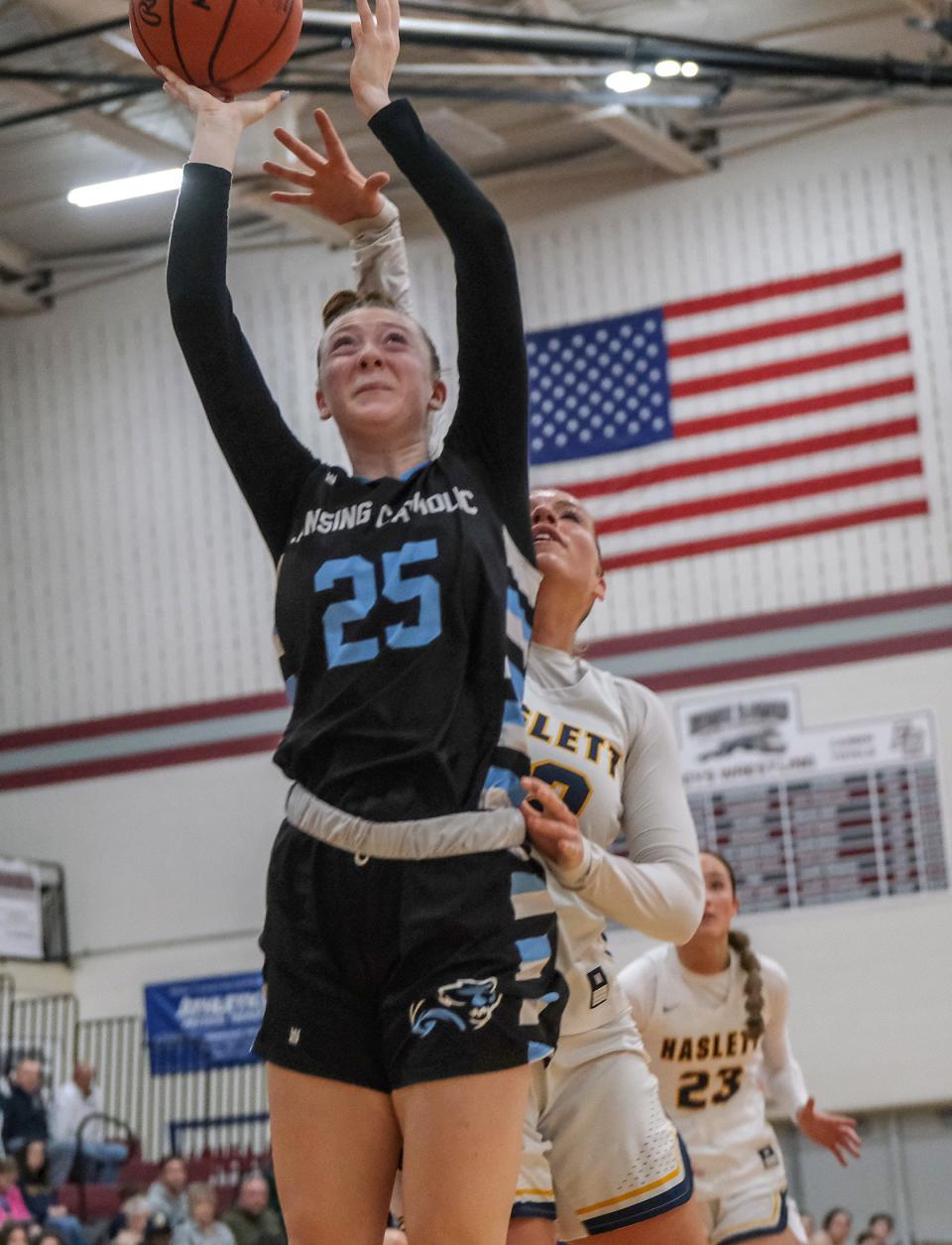 Lansing Catholic's Morgan Wilcox (25) shoots as Haslett's Grace Isenhath (32) defends in district final play Saturday, Mar. 4, 2023.