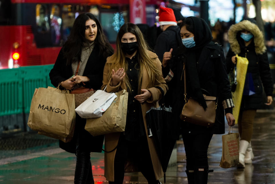 Shoppers wear face masks as they walk in Oxford Street, ahead of the new Tier-4 restriction measures, on December 19, 2020 in London, England.  Britain's Prime Minister Boris Johnson says Christmas gatherings cannot go ahead and non-essential shops must close in London and much of southern England as he imposed a new, higher level of coronavirus restrictions to curb rapidly spreading infections. (Photo by Maciek Musialek/NurPhoto via Getty Images)