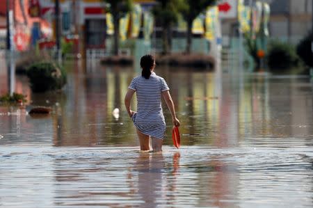 A woman makes her way in a flooded area in Mabi town in Kurashiki, Okayama Prefecture, Japan, July 8, 2018. REUTERS/Issei Kato