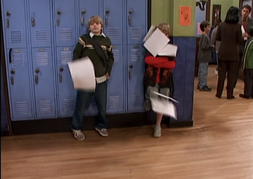 Cody throws a bunch of papers in the air in a school hallway after being scared by something