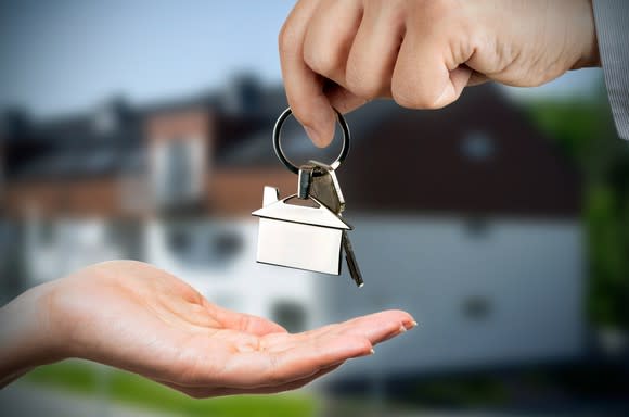 A person handing house keys to another person