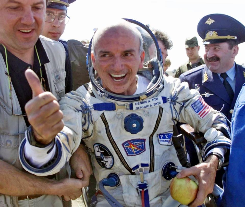 American multimillionaire  Dennis Tito, 60, gestures shortly after his landing on the steppes, 80 kilometers (50 miles) northeast of Arkalyk, Kazakstan, Sunday, May 6, 2001. Others are unidentified. The Russian Soyuz capsule carrying the world's first paying space tourist landed successfully on Sunday, ending Tito's multimillion dollar cosmos adventure. (AP Photo/Mikhail Metzel)