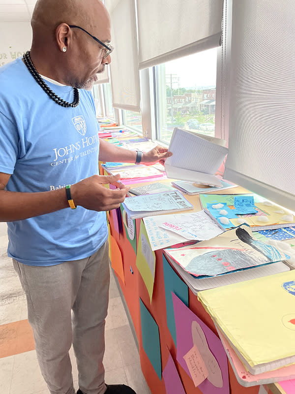 Brother Modlin holds one of the many student journals he keeps on display in his classroom. “These books are their personalities,” he said. (Asher Lehrer-Small)