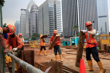 Workers carry pieces of wood as walks at the Jakarta Mass Rapid Transit construction at Sudirman Business District in Jakarta, Indonesia, April 17, 2018. REUTERS/Beawiharta