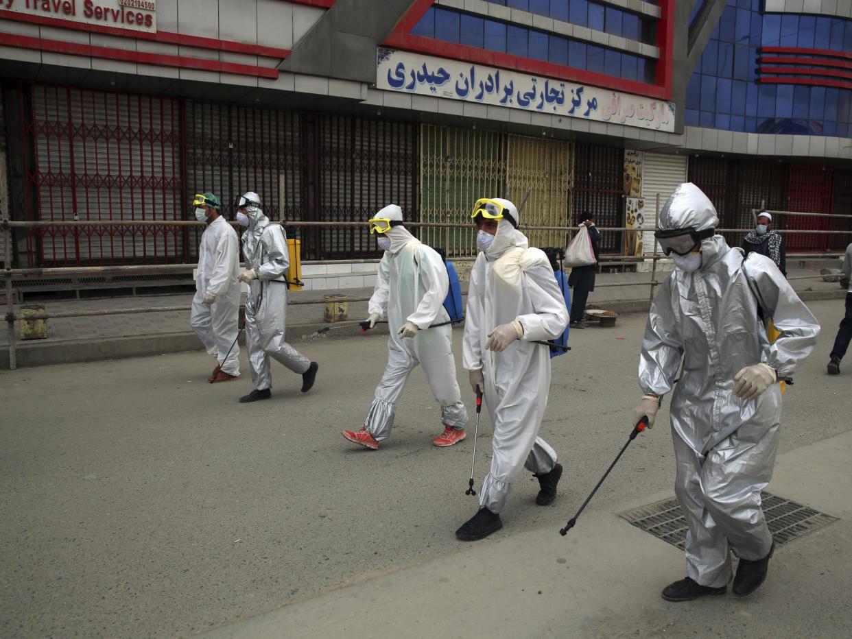 Volunteers in protective suits spray disinfectant on storefronts to help curb the spread of the coronavirus in Kabul, Afghanistan: AP