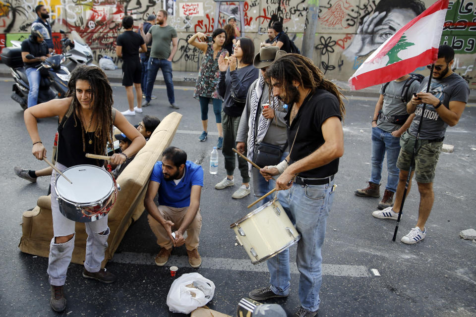 Anti-government protesters bang on drums as they block a main highway in Beirut, Lebanon, Wednesday, Nov. 13, 2019. A local official for a Lebanese political party was shot dead by soldiers trying to open a road closed by protesters in southern Beirut late Tuesday, the army reported, marking the first death in 27 days of nationwide protests. (AP Photo/Bilal Hussein)