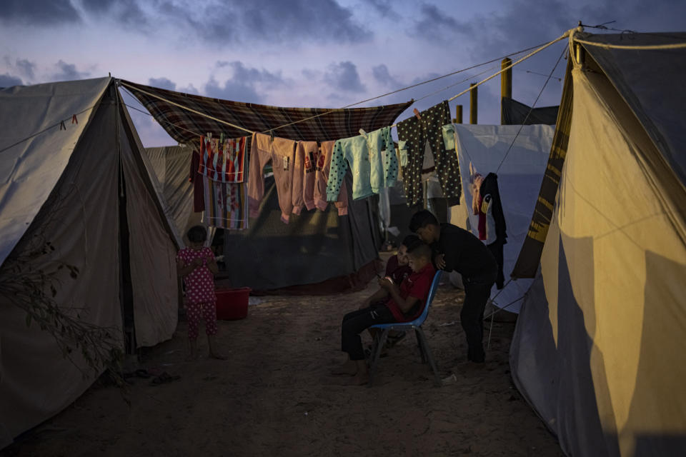 FILE - Palestinian kids who were displaced by the Israeli bombardment of the Gaza Strip watch at a phone in a UNDP-provided tent camp in Khan Younis, Wednesday, Nov. 1, 2023. With the Israel-Hamas war in its second month and more than 10,000 people killed in Gaza, trapped civilians are struggling to survive without electricity or running water. Each day has become a mind-numbing cycle of searching for bread and water and waiting in lines. A sense of desperation has strained Gaza's close-knit society. (AP Photo/Fatima Shbair, File)