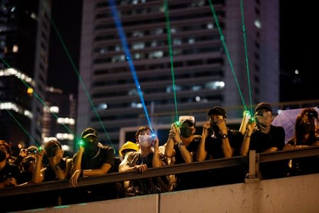 Manifestantes contra el proyecto de ley de extradición apuntan punteros láser durante una marcha para exigir democracia y reformas políticas en Hong Kong.