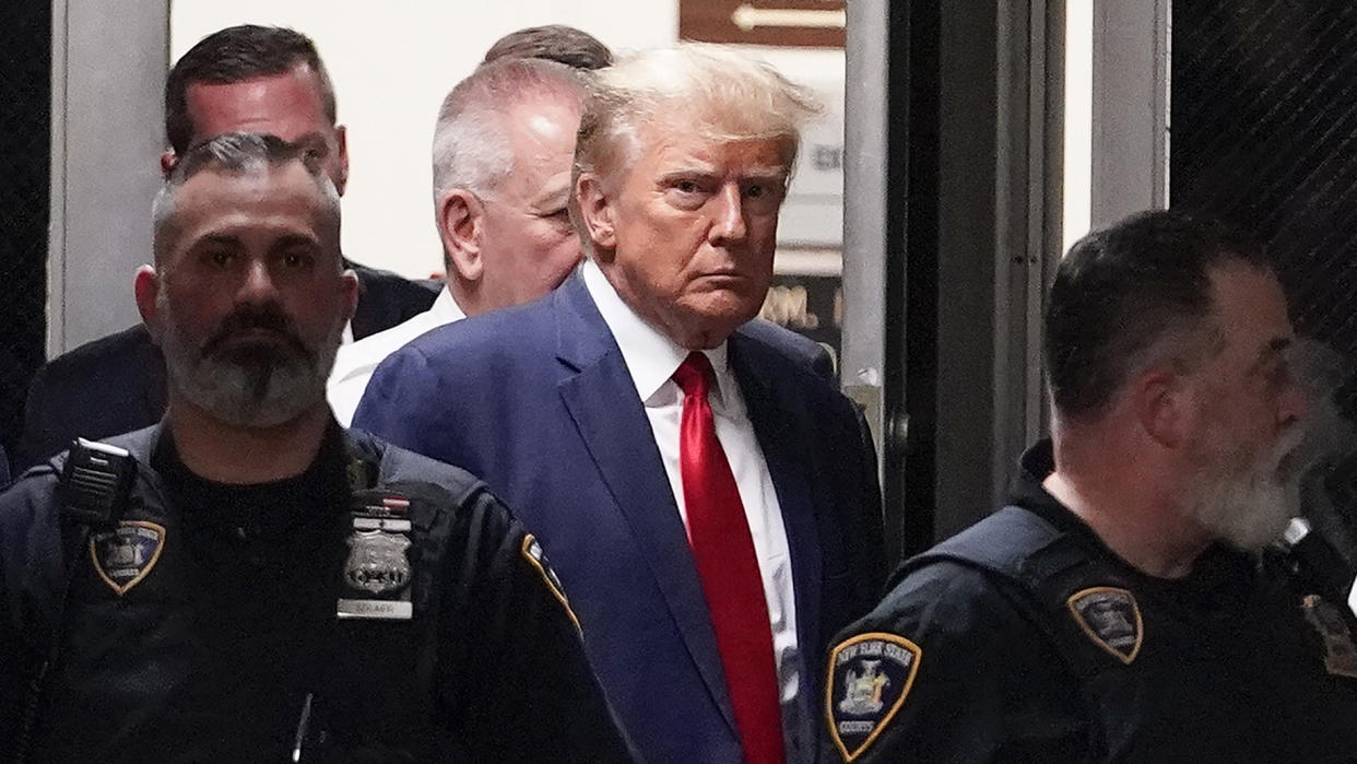 Former President Donald Trump arrives at court in Manhattan on April 4, 2023, surrounded by uniformed police officers.