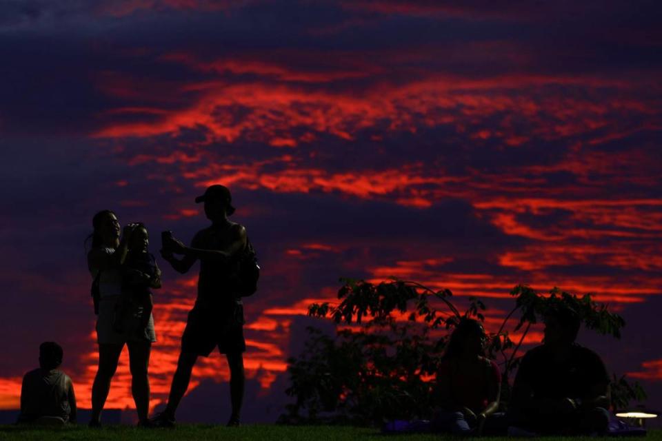 People are seen lying and standing on the grass of the amphitheater as the sun sets during the inauguration of the eastern portion of Doral Central Park at 3005 NW 92nd Ave. in Doral, Florida, on Monday, Aug. 26, 2024.