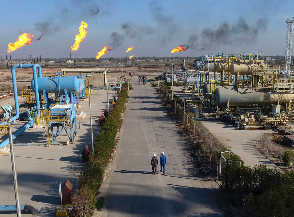 FILE - In this Thursday Jan. 12, 2017 file photo, workers walk in the Nihran Bin Omar field north near Basra, Iraq. An Iraqi oil official says employees of energy giant Exxon Mobil have started evacuating an oil field in the southern province of Basra, amid rising tensions between the United States and Iran. The first group left two days ago and another batch left early Saturday May 18, 2019. (AP Photo/Nabil al-Jurani, File)