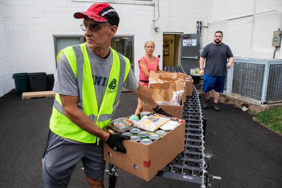 From left, Phil Diego, wife Marguerite Diego and Eric, who are volunteers at the Greenbank Church of Christ drive-thru food pantry in Prices Corner, carry boxes of food to meal recipients on Thursday, Aug. 25, 2022. The pantry serves free meals to the community and continues to follow COVID-19 protocols.