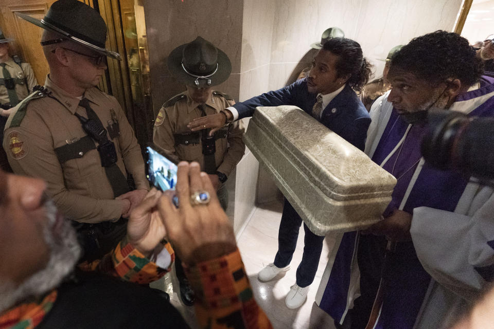 Rep. Justin Jones, D-Nashville, with Rev. William J. Barber, right, try to get past state troopers while carrying a coffin on their way to the House chambers, Monday, April 17, 2023, in Nashville, Tenn. (AP Photo/George Walker IV)