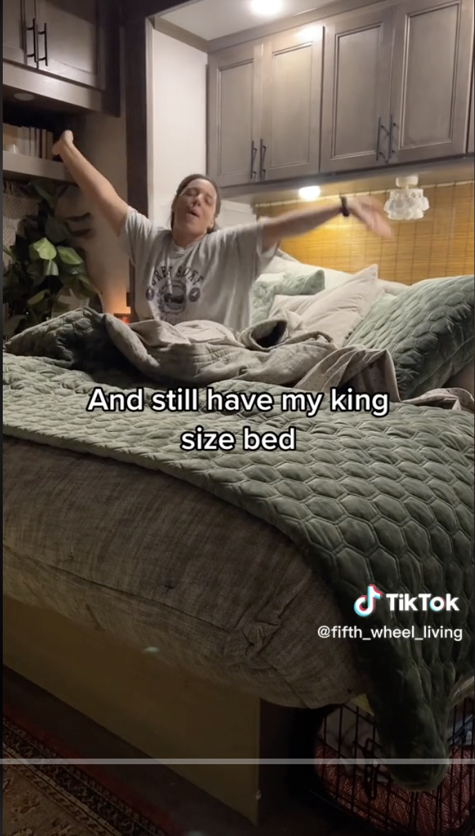 Kirs sitting on the king-size bed with her arms outstretched