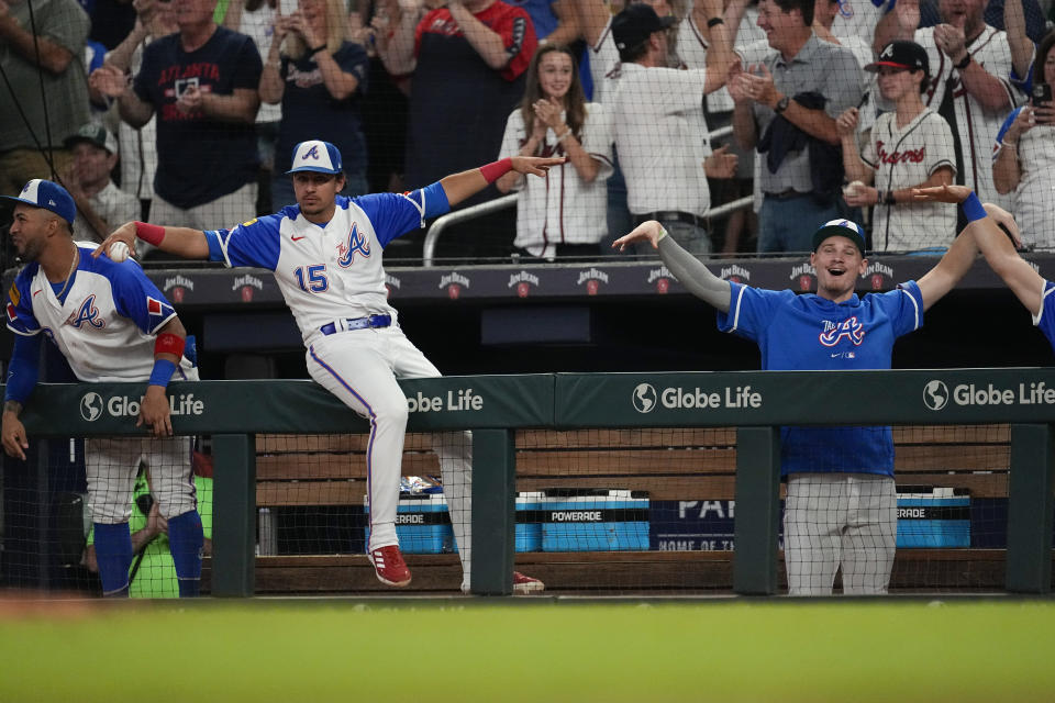 Atlanta Braves players from left to right; Eddie Rosario, Travis d'Anraud and AJ Smith-Shawver react in the dugout after a Marcell Ozuna thgree-run home run in the fifth inning of a baseball game against the Washington Nationals, Saturday, Sept. 30, 2023, in Atlanta. (AP Photo/John Bazemore)