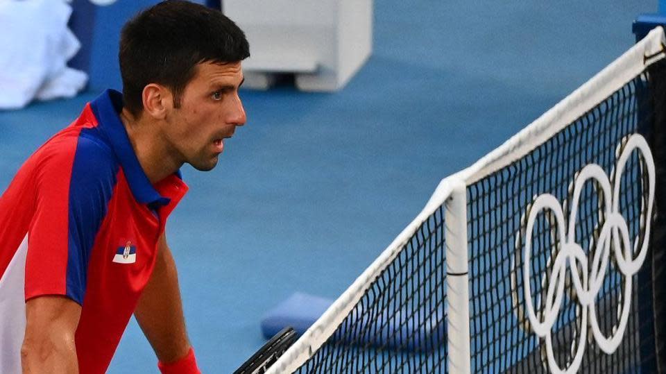 Novak Djokovic at the net with the Olympic rings