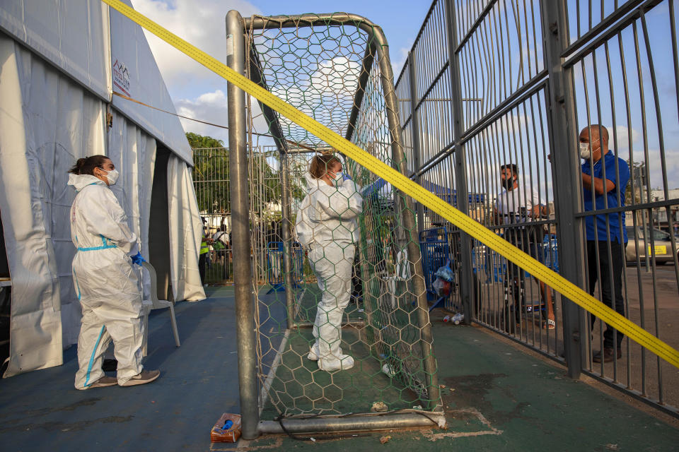 Image: Israeli healthcare workers at a testing center for migrants in Tel Aviv on Monday. (Oded Balilty / AP)