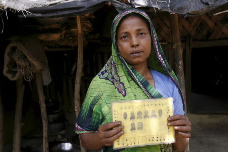 Rupban, a Rohingya woman, shows her ration card with pictures of her family members at a refugee camp in Kutupalong May 31, 2015. REUTERS/Rafiqur Rahman