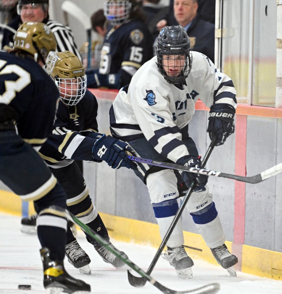 Harley Ellis of Sandwich dishes off the puck past Ryan Hill of Saint Bernard's in Div.4 Round of 32 hockey on March 3.
