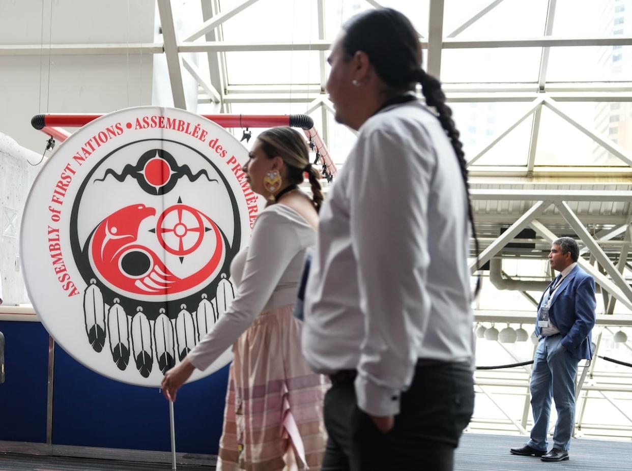 Attendees walk past a banner at the Assembly of First Nations annual general assembly in Montreal, Tuesday. (Christinne Muschi/The Canadian Press - image credit)